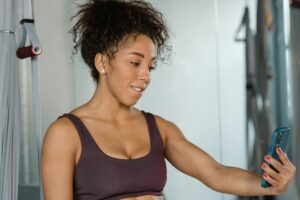 Fit woman using fitness app on smartphone at gym